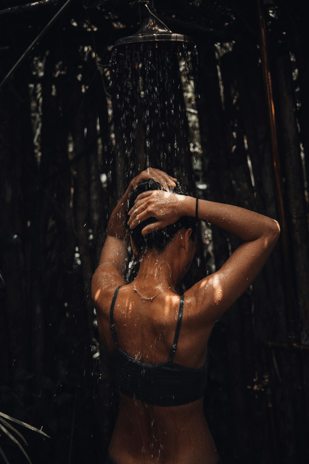 Woman with defined wet curls washing her hair in a bright bathroom