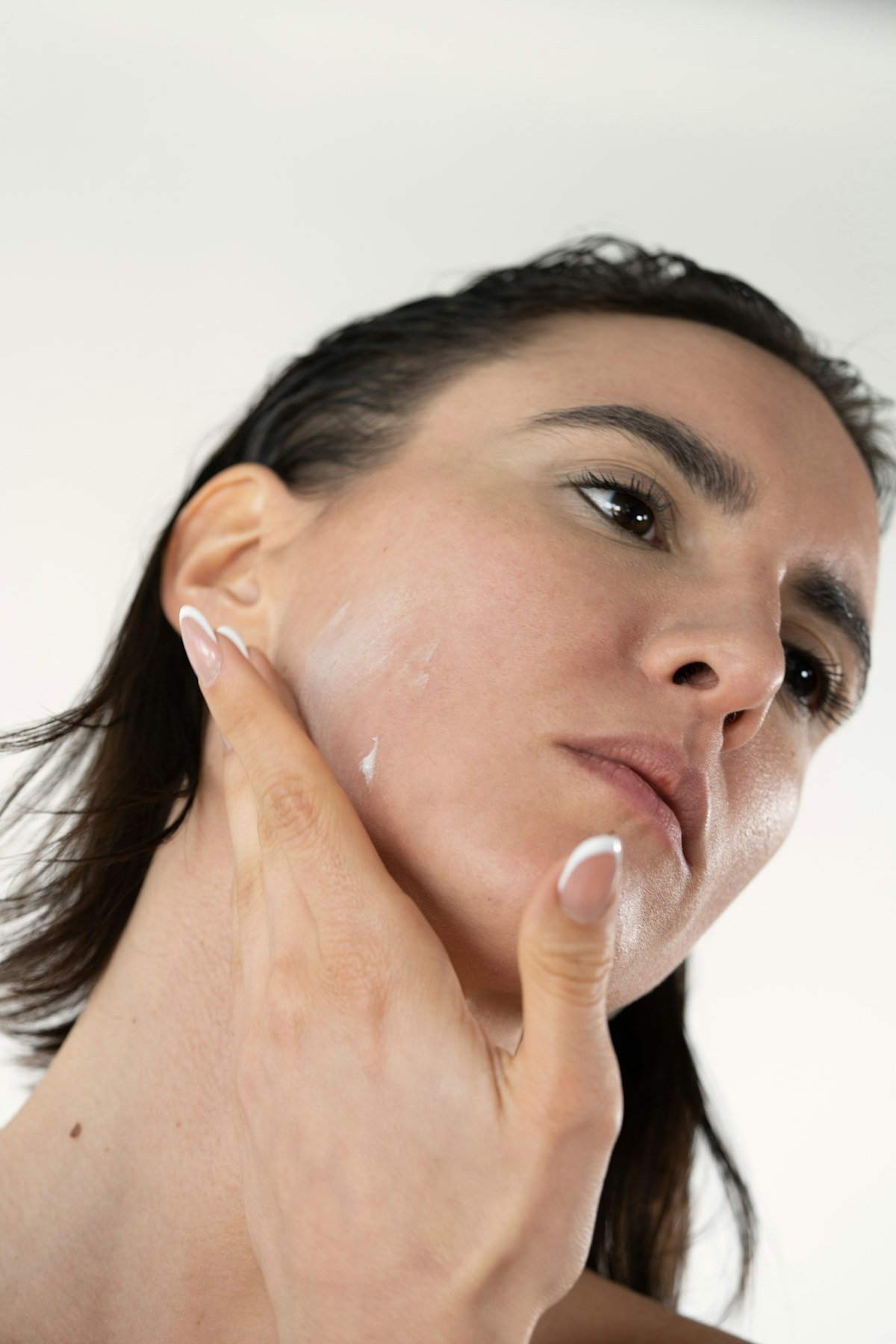 Woman applying sunscreen at her vanity before doing her makeup, foundation and brushes laid out ready