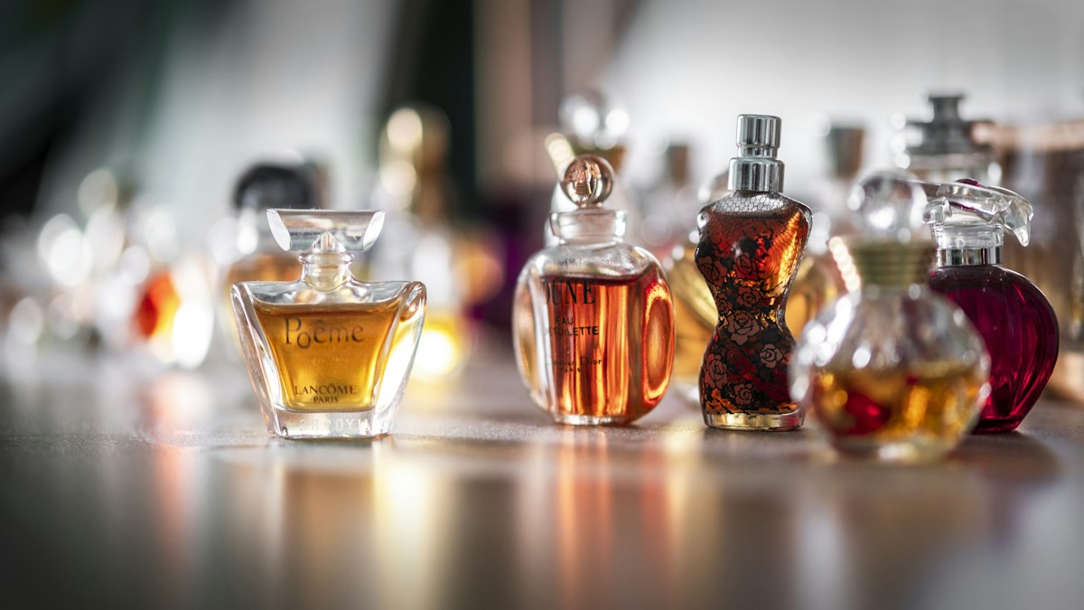 Collection of perfume bottles and scented body lotion arranged on a bedroom dresser
