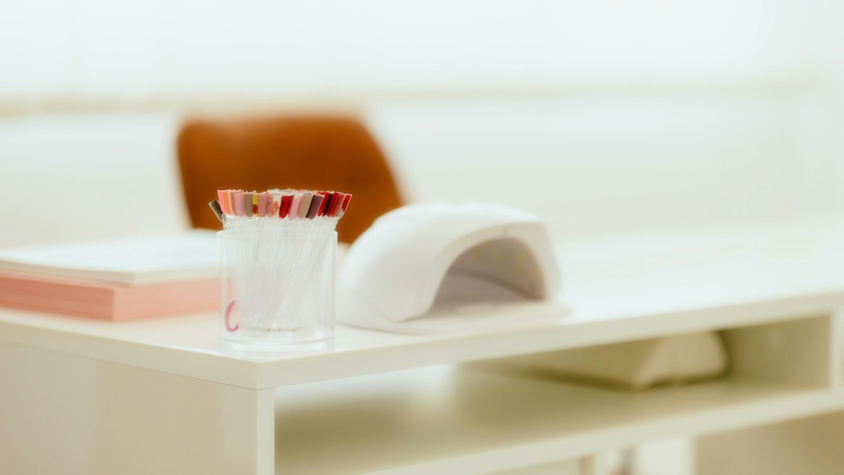 Home gel manicure setup with UV lamp and polish bottles on a kitchen table