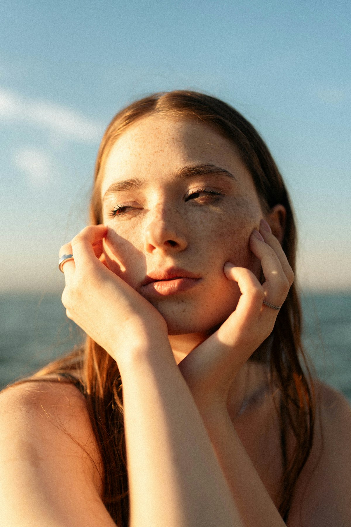 Woman blending tinted moisturizer into her skin with her fingers in natural window light